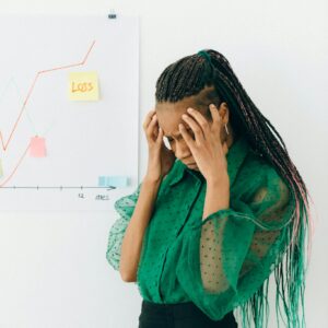 Businesswoman in distress over financial graph showing loss indoors.