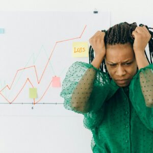 Frustrated businesswoman in green blouse analyzing a graph showing financial loss.